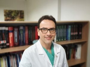 Prof. Dr. Uğur Boylu ofiste kütüphane önünde duruyor.